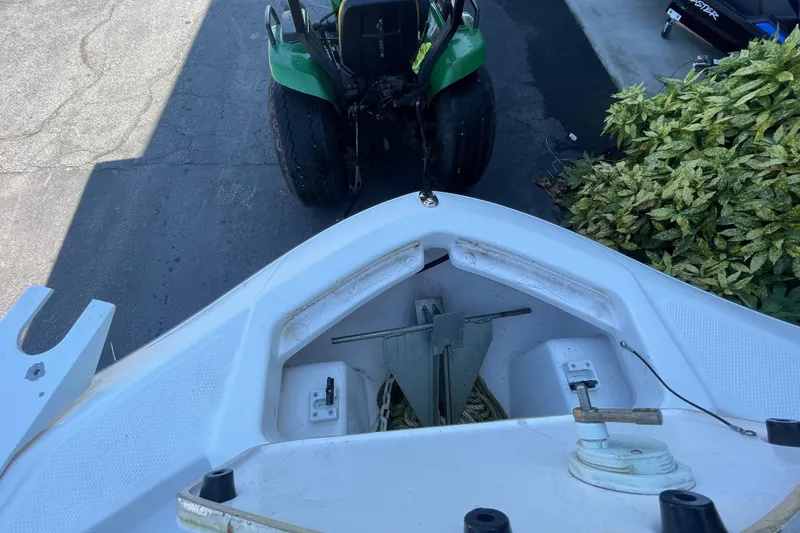 Slide: The Image of 2021 Yamaha Boats 195 FSH Sport bow with anchor storage, near a green tractor. - 16
