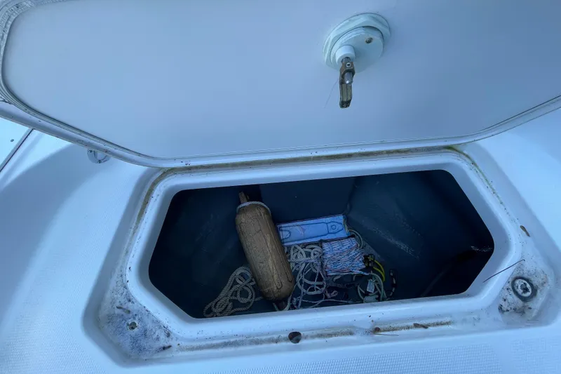 Slide: The Image of Open storage compartment on 2021 Yamaha Boats 195 FSH Sport, containing ropes and a fender. - 17