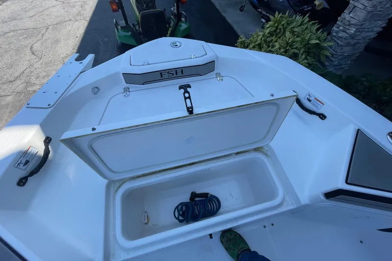 Slide: The Image of 2021 Yamaha Boats 195 FSH Sport storage compartment with open lid and coiled rope inside. - 18