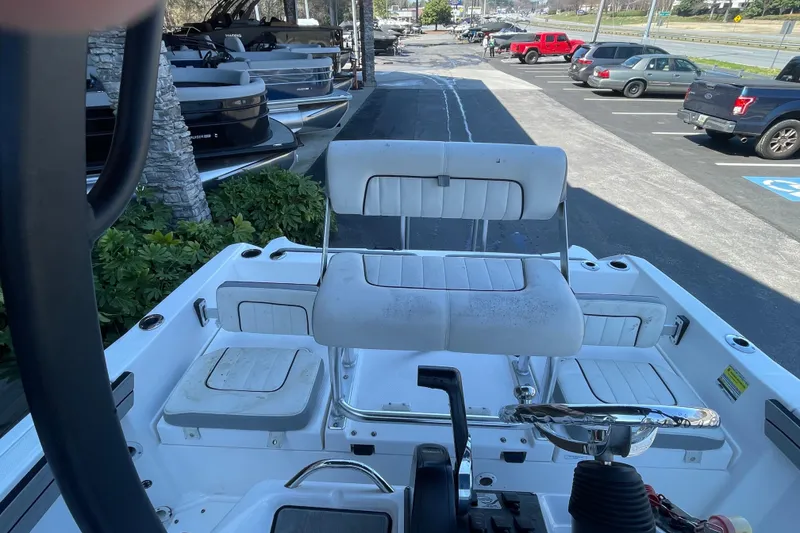 Slide: The Image of 2021 Yamaha Boats 195 FSH Sport interior with seating and steering wheel, parked outdoors. - 27