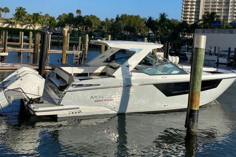 The Image of 2022 Monterey 385 Super Express boat docked in a marina, surrounded by palm trees. - 1