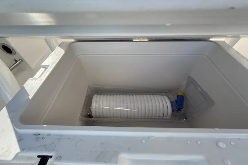 Slide: The Image of 2026 Robalo R200 Center Console storage compartment with coiled hose inside. - 14