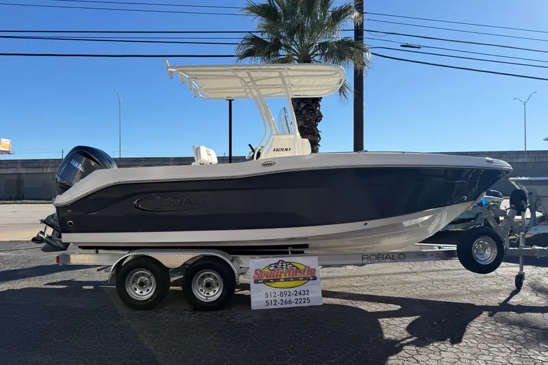 Slide: The Image of 2026 Robalo R200 Center Console boat on trailer, displayed outdoors under clear blue sky. - 48