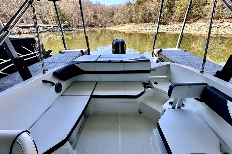 Slide: The Image of 2015 Sea Ray 21 SPX OB boat interior with white seating, docked on a calm lake. - 5