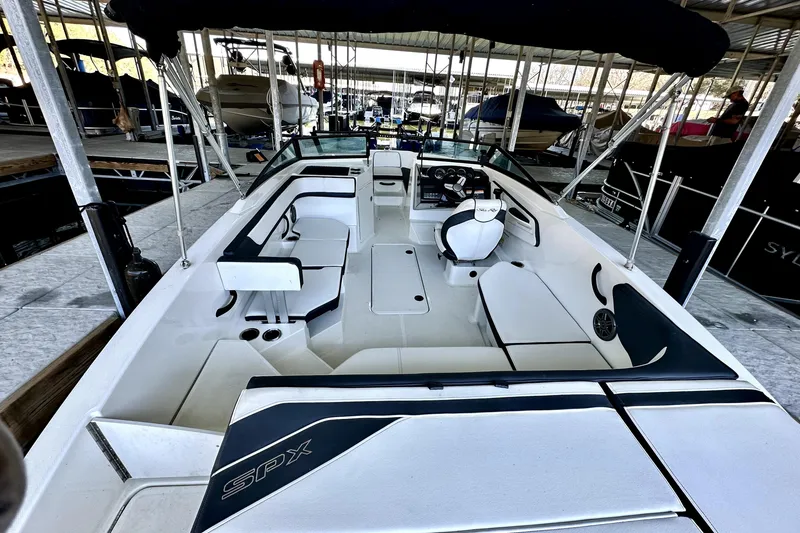 Slide: The Image of 2015 Sea Ray 21 SPX OB boat interior with seating and steering wheel in marina. - 6