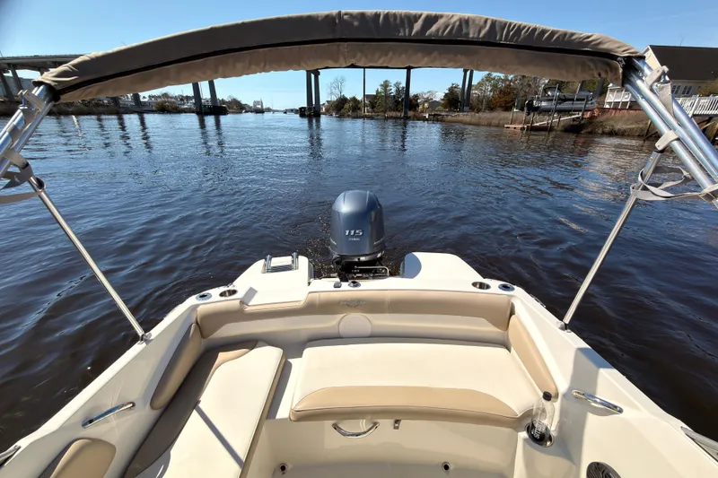 Slide: The Image of 2018 Stingray 191 DC boat with canopy on a calm river, featuring a 115 HP motor. - 15