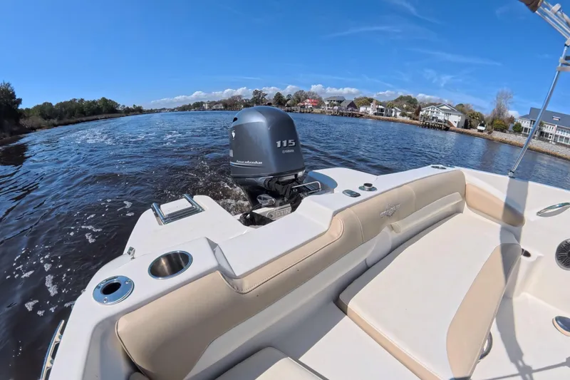 Slide: The Image of 2018 Stingray 191 DC boat cruising on a scenic river with waterfront homes. - 16