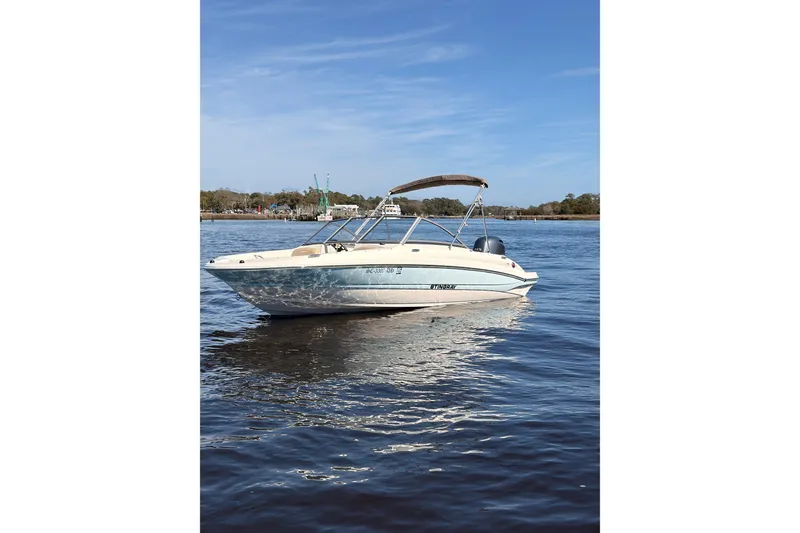 Slide: The Image of 2018 Stingray 191 DC boat on calm water under clear blue sky. - 2