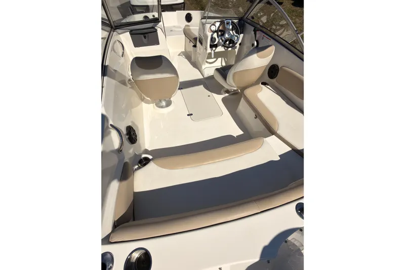 Slide: The Image of 2018 Stingray 191 DC boat interior with beige seating and steering console. - 7