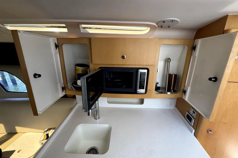 Slide: The Image of 2014 Intrepid 400 Cuddy kitchen with microwave, sink, and open cabinets. - 24
