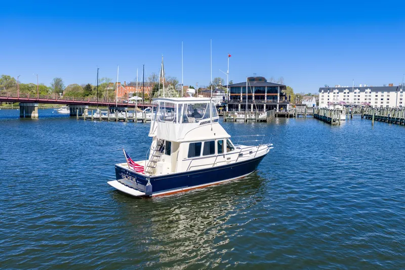 Slide: The Image of 2006 Sabreline 36 Fly yacht on calm waters near a marina and bridge. - 111
