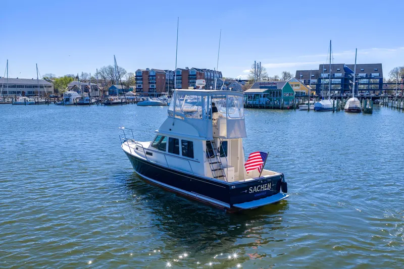 Slide: The Image of 2006 Sabreline 36 Fly yacht in a marina, with buildings and boats in the background. - 119