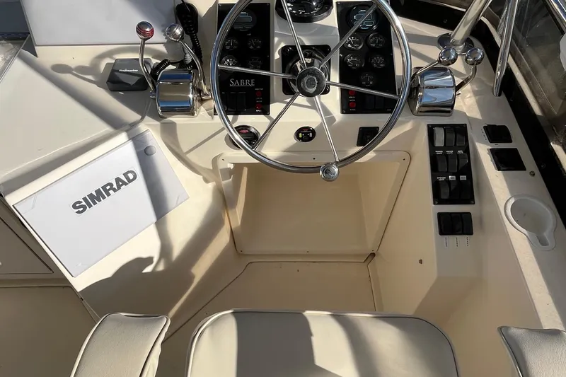 Slide: The Image of 2006 Sabre 36 Flybridge Sedan helm with steering wheel, controls, and Simrad equipment. - 13