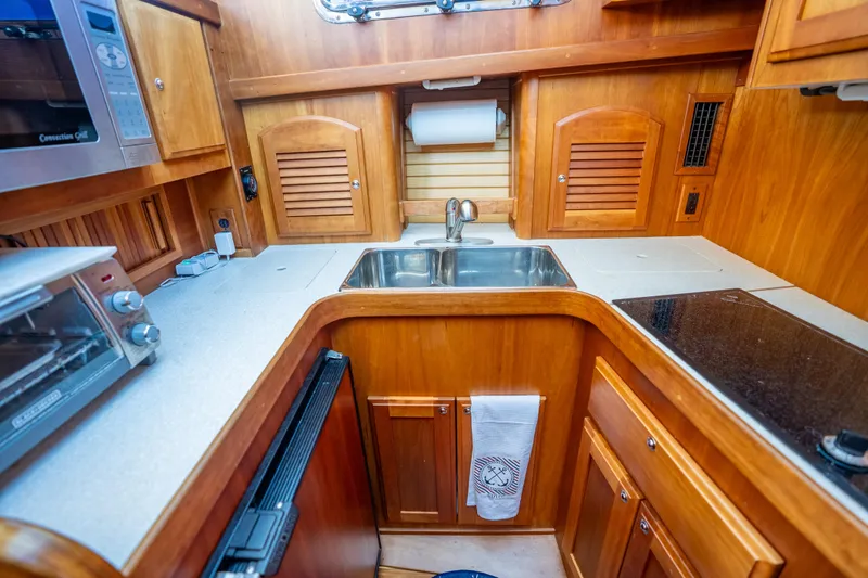 Slide: The Image of Compact kitchen in a 2006 Sabreline 36 Fly yacht with wooden cabinetry and modern appliances. - 93