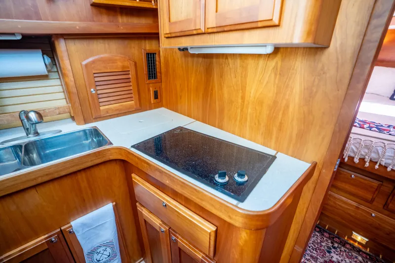 Slide: The Image of 2006 Sabreline 36 Fly yacht kitchen with wooden cabinetry and modern stovetop. - 94