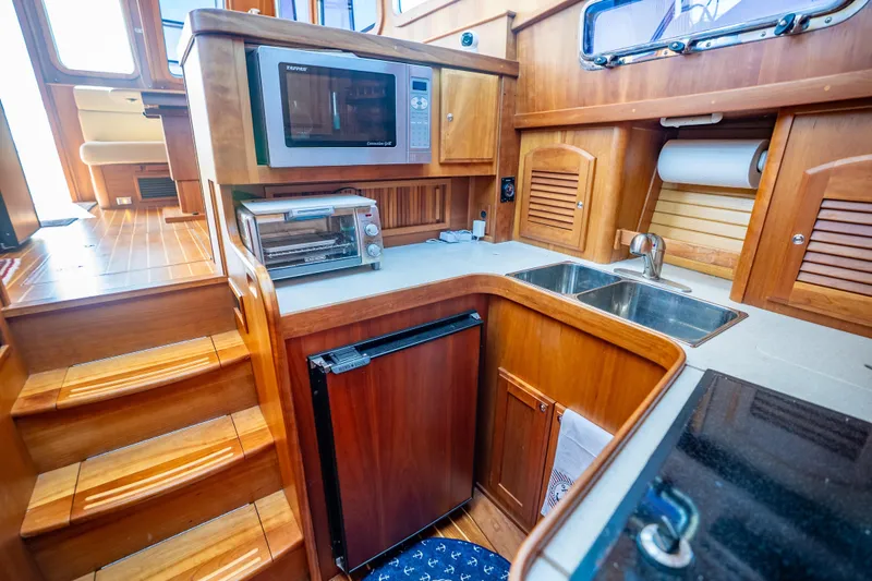 Slide: The Image of 2006 Sabreline 36 Fly yacht kitchen with microwave, toaster oven, and wooden cabinetry. - 95