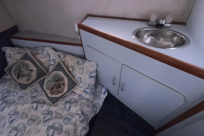 Slide: The Image of 1989 Searay 30 Sedan Bridge cabin interior with bed, pillows, and sink. - 12