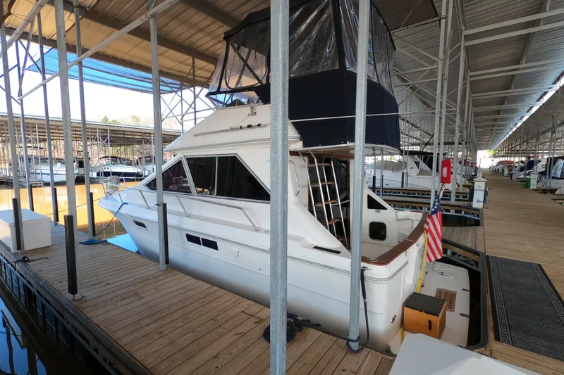 Slide: The Image of 1989 Searay 30 Sedan Bridge docked in a covered marina, featuring an American flag. - 4
