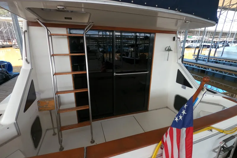 Slide: The Image of 1989 Searay 30 Sedan Bridge boat with ladder and American flag at dock. - 5