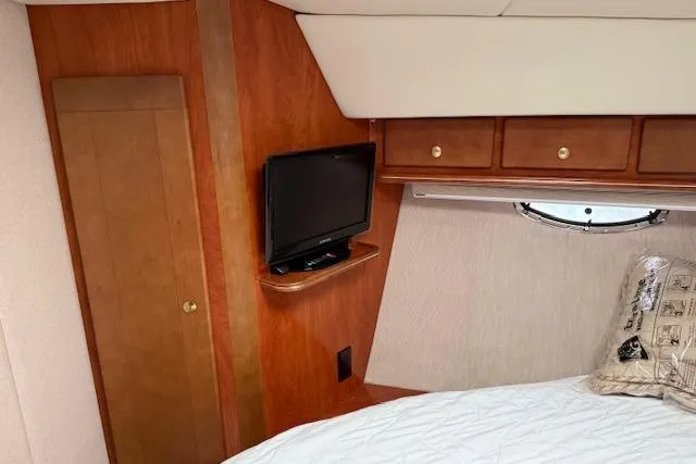 Slide: The Image of 2006 Rinker Fiesta Vee 410 cabin interior with TV, wood cabinetry, and bed. - 10