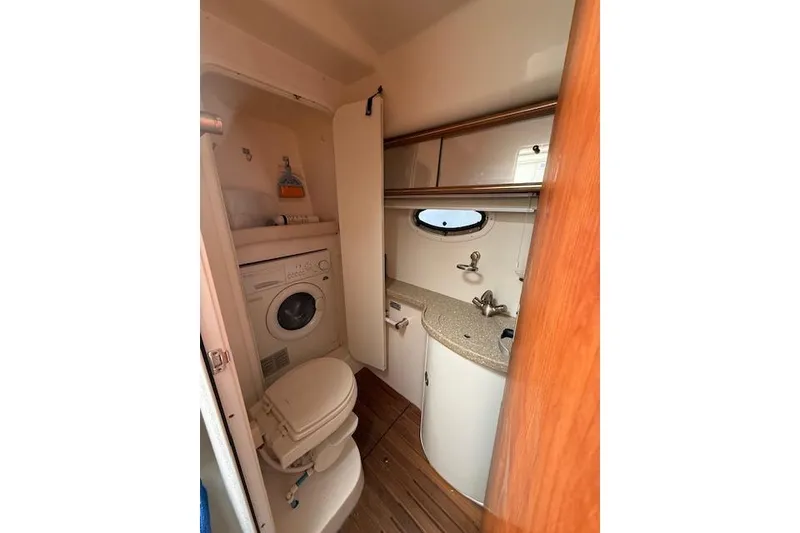 Slide: The Image of 2006 Rinker Fiesta Vee 410 bathroom with washer, toilet, sink, and storage cabinets. - 15