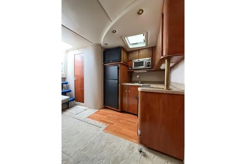 Slide: The Image of 2006 Rinker Fiesta Vee 410 interior with kitchenette, featuring wood cabinetry and modern appliances. - 16