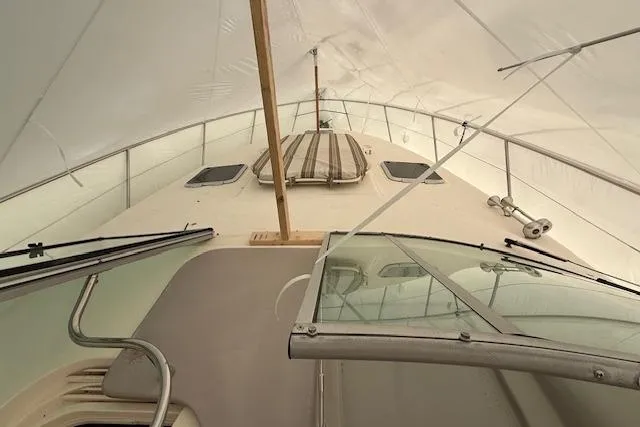 Slide: The Image of 2006 Rinker Fiesta Vee 410 boat under cover, showcasing deck and windshield. - 34