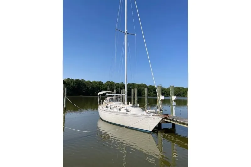 The Image of 1980 Sabre 34 MK II sailboat docked on calm water under clear blue sky. - 0