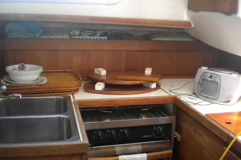 Slide: The Image of 1980 Sabre 34 yacht kitchen with stove, sink, and wooden cabinetry. - 61