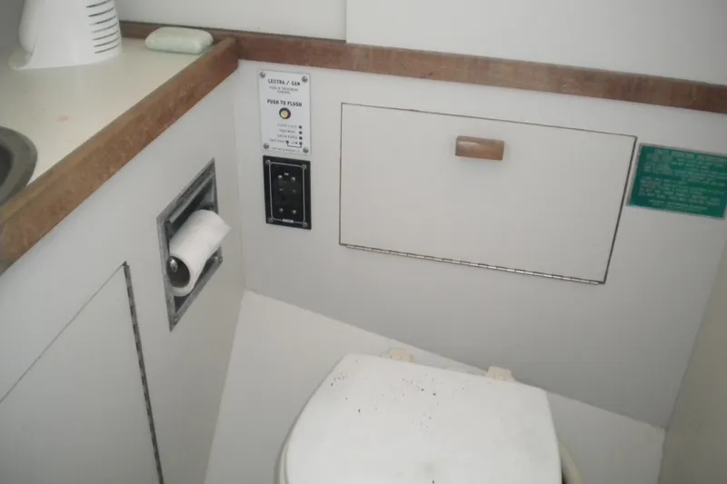 Slide: The Image of 1980 Sabre 34 yacht bathroom with toilet, flush controls, and toilet paper holder. - 64
