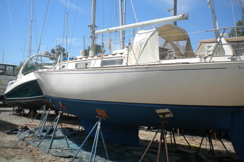 Slide: The Image of 1980 Sabre 34 sailboat on stands, white hull, blue bottom, in a boatyard. - 67
