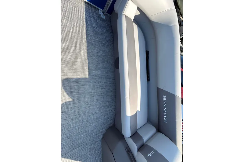 Slide: The Image of 2024 Bennington SVL pontoon boat interior with gray seating on a calm river. - 13