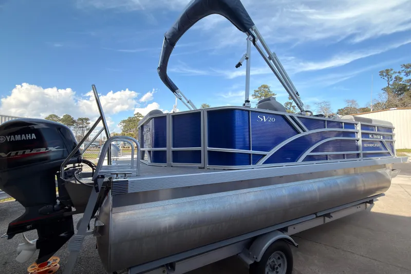 Slide: The Image of 2024 Bennington SVL pontoon boat with Yamaha engine on a trailer, under a clear sky. - 2