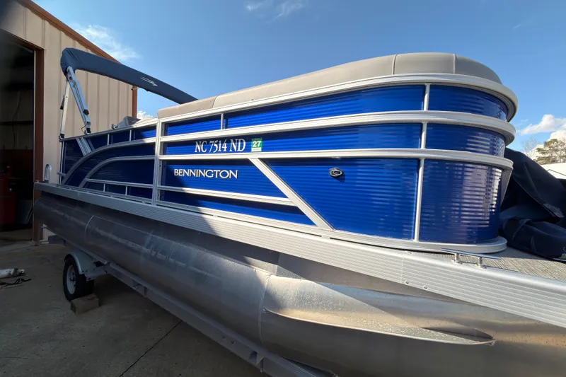Slide: The Image of 2024 Bennington SVL pontoon boat with blue exterior, parked outside a building. - 3