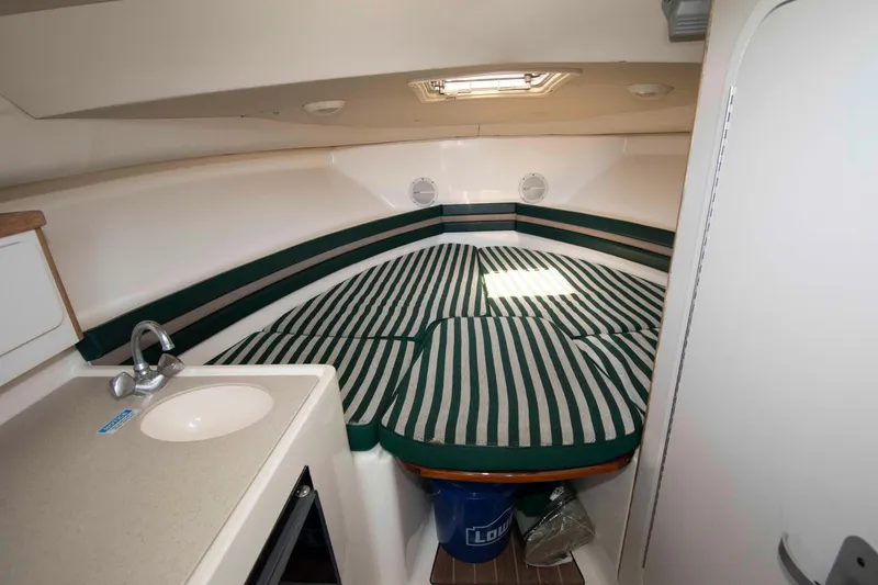 Slide: The Image of 2000 Pursuit 2860 Denali cabin interior with striped bedding and compact sink area. - 12