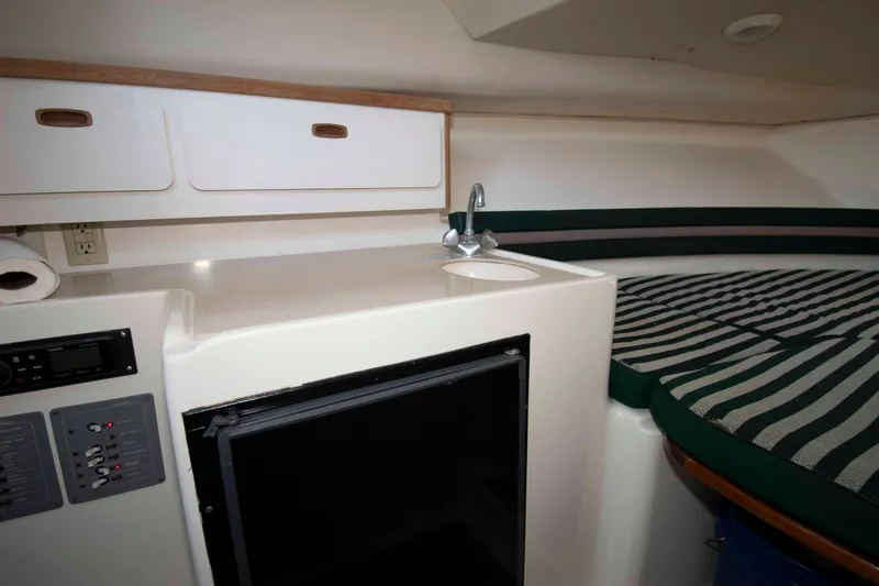 Slide: The Image of 2000 Pursuit 2860 Denali cabin interior with kitchenette, sink, and striped seating area. - 14