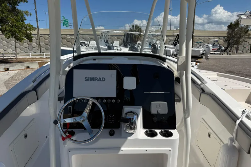 Slide: The Image of 2022 Aquasport 2300 Center Console boat dashboard with Simrad display and steering wheel. - 7