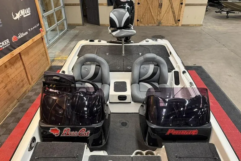 Slide: The Image of 2010 Bass Cat Puma boat interior with dual seats and console in a showroom. - 14