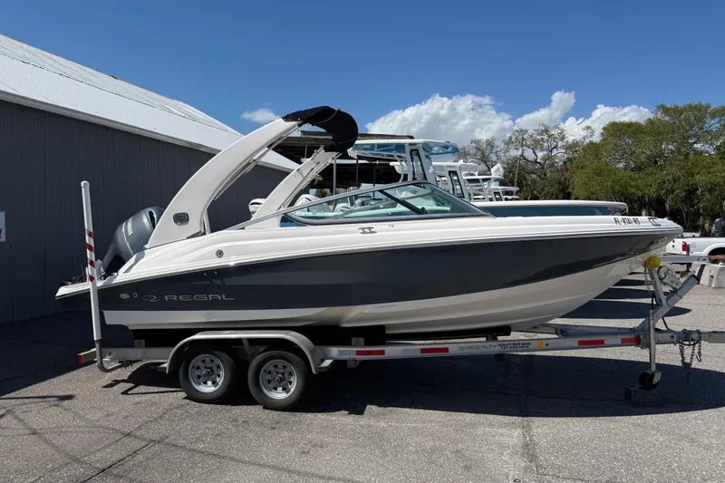 The Image of 2019 Regal 21 OBX boat on trailer, parked outdoors under clear sky. - 1