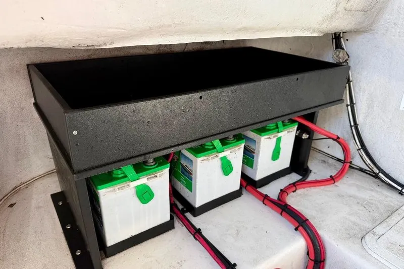 Slide: The Image of Battery compartment of 2007 Cape Horn 24 OS boat with three batteries and red cables. - 12