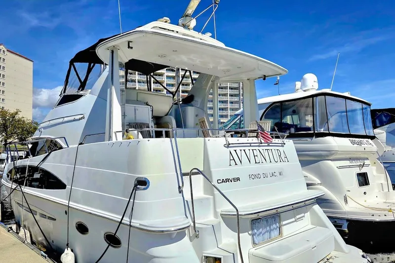 Slide: The Image of 2000 Carver 396 Motor Yacht docked, named "Avventura," with clear blue sky background. - 3