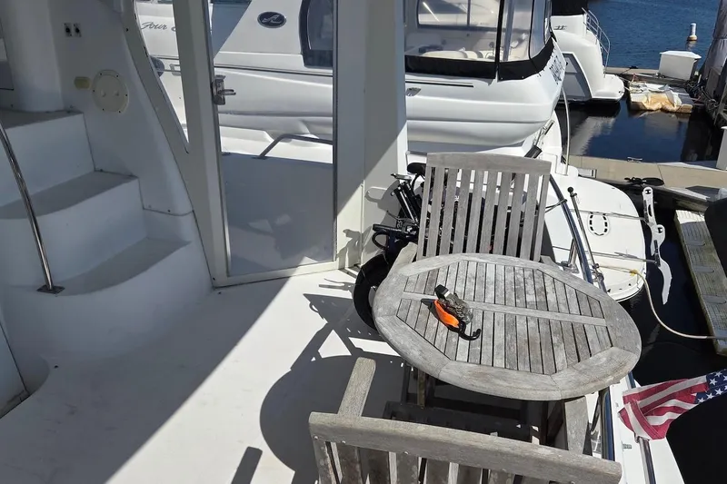 Slide: The Image of 2000 Carver 396 Motor Yacht deck with wooden table and chairs, docked at marina. - 5