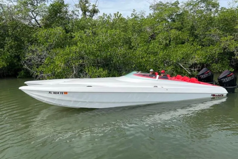 The Image of 2020 HellKats 30 boat with red interior, docked in a lush, green waterway. - 0