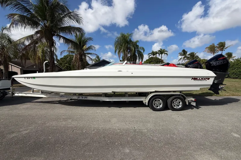 Slide: The Image of 2020 HellKats 30 powerboat on trailer, parked near palm trees under a blue sky. - 10