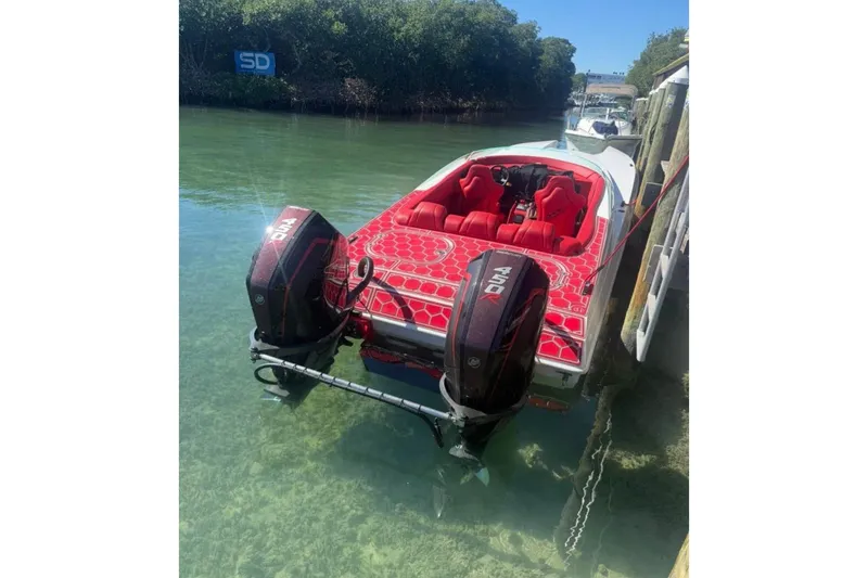 Slide: The Image of 2020 HellKats 30 boat with red interior and dual outboard motors docked in clear water. - 2