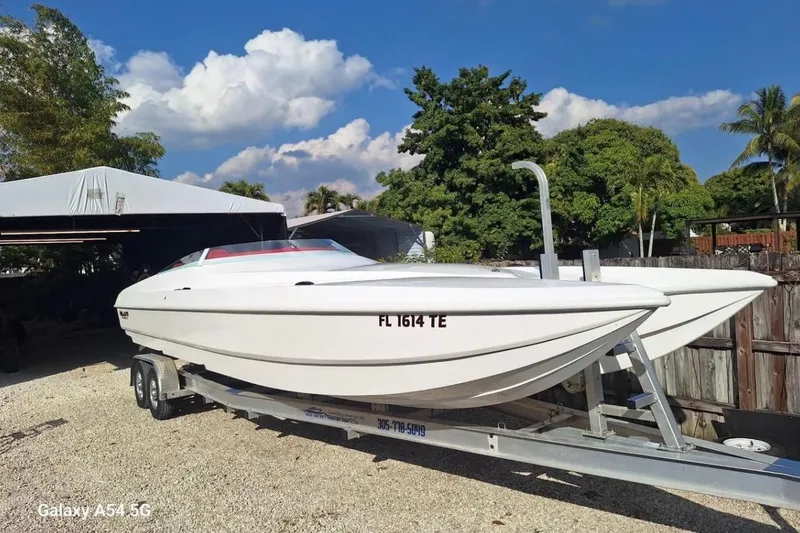 Slide: The Image of 2020 HellKats 30 powerboat on trailer, parked in a tropical residential area. - 6