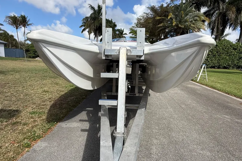 Slide: The Image of 2020 HellKats 30 boat on trailer, parked outdoors with palm trees in background. - 7