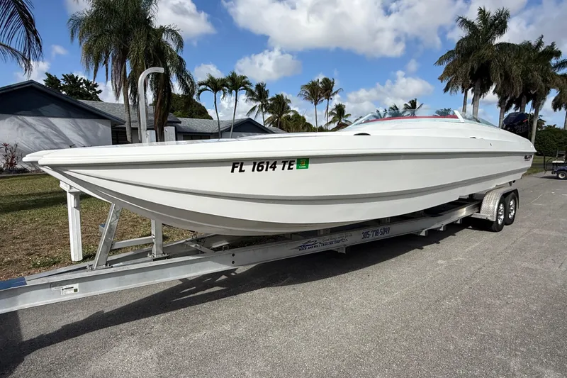 Slide: The Image of 2020 HellKats 30 boat on trailer, parked outdoors with palm trees in background. - 9