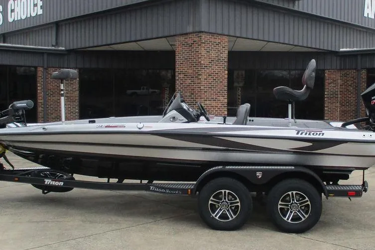 The Image of 2026 Triton 19 TrX Patriot boat on trailer, parked outside a building. - 1