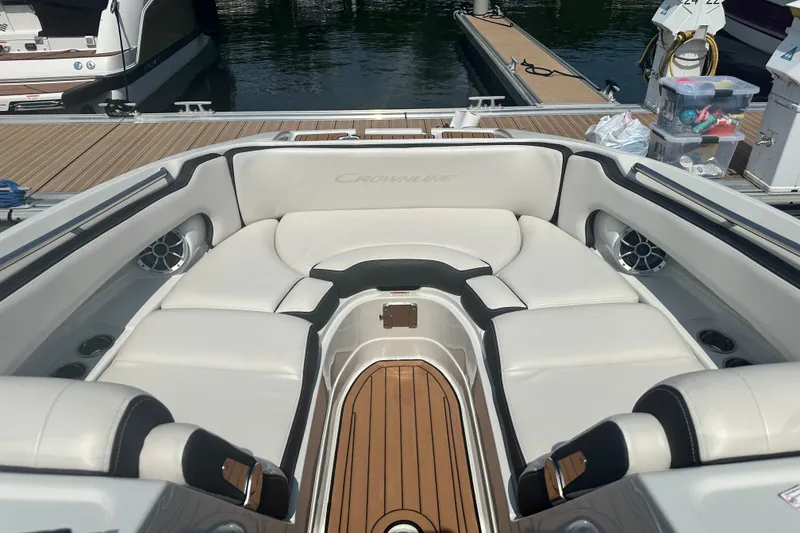 Slide: The Image of 2023 Crownline Eclipse E255 boat interior with white seating and wood accents at dock. - 10